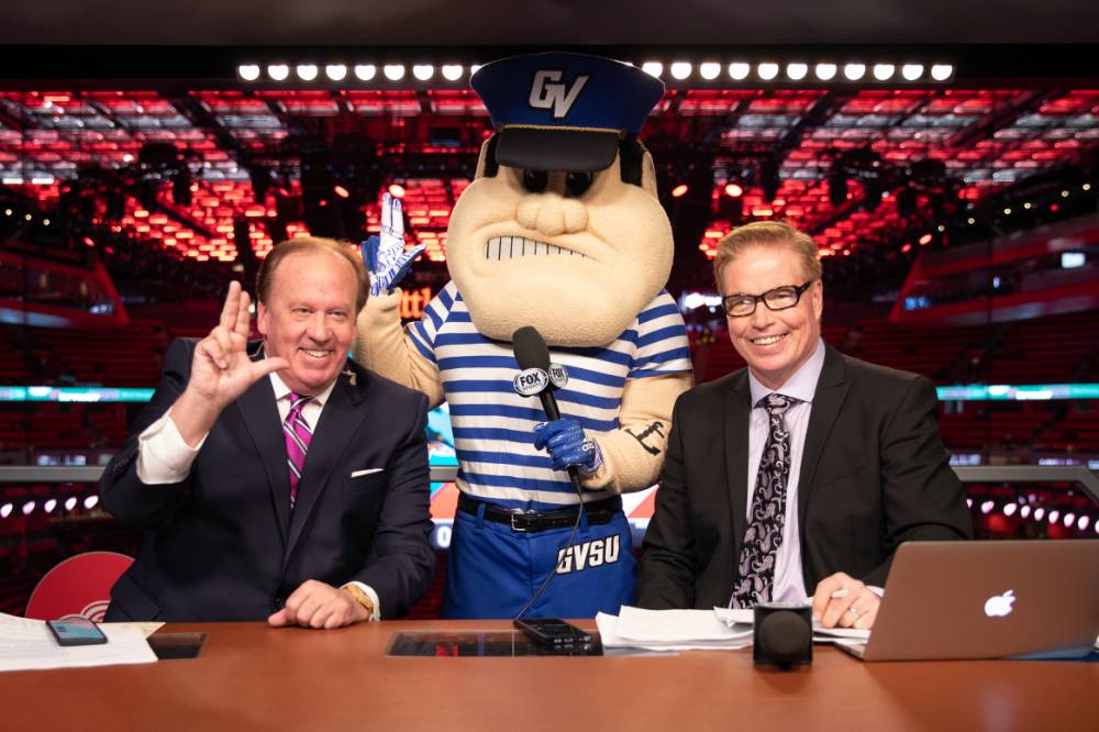 Louie and a broadcaster do the hand gesture for Lakers at the Detroit Red Wings GVSU Night